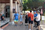 Grupo de turistas camina por una calle del Centro Histórico de Mazatlán, frente a un edificio con columnas y locales comerciales, durante su visita al puerto tras el arribo de un crucero en el Carnaval 2026.