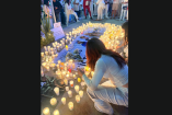 Personas vestidas de blanco encienden velas alrededor de un memorial con fotografías y flores durante una concentración por la paz en el Parque Sendela, en Angelópolis, Puebla, tras la balacera frente al bar Sala de Despecho.