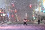 Peatones cruzan una calle en Times Square, Manhattan, bajo fuerte nevada y semáforos en rojo durante una tormenta invernal que impactó Nueva York el 22 de febrero de 2026, con baja visibilidad y acumulación de nieve en la calzada.