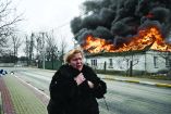 (FILES) A woman reacts as she stands in front of a house burning after being shelled in the city of Irpin, outside Kyiv, on March 4, 2022. More than 1.2 million people have fled Ukraine into neighbouring countries since Russia launched its full-scale invasion on February 24, United Nations figures showed on March 4, 2022. (Photo by Aris Messinis / AFP)