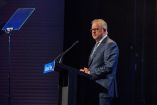 Anthony Albanese pronuncia un discurso en el Future Victoria Summit en Melbourne, de pie tras un atril con micrófono y teleprompter, en un escenario con iluminación tenue y fondo oscuro.
