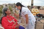 Trabajadora de salud realiza revisión médica a adulta mayor en su domicilio rural, utilizando equipo básico para diagnóstico preventivo