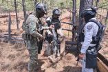 Elementos de la Secretaría de Marina inspeccionan un arma larga asegurada en zona boscosa de Del Nayar durante operativo contra enervantes.