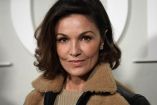 La actriz francesa Nadia Farès posa en primer plano durante un evento de moda en París, con chaqueta oscura y fondo desenfocado.