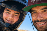Mateo Díaz con casco de motocross posa junto a su padre Homero Díaz en una fotografía cercana, ambos sonrientes durante una jornada deportiva.