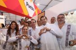 Funcionarios y promotores de Puebla posan en stand del Tianguis Turístico con vestimenta tradicional y logotipo del estado visible en el recinto