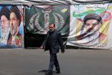 Un hombre pasa junto a pancartas colocadas a lo largo de la carretera con la imagen del ayatolá Ali Khamenei