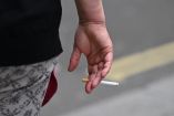 (FILES) A person is seen smoking a cigarette in central London on June 9, 2022. The British Parliament has passed a law aimed at making the UK a progressively tobacco-free country by banning the sale of cigarettes for life to anyone born after 2008  a first in Europe. Here are five things to know about this law, which the government has hailed as "historic" and which advocacy groups have praised as a major turning point. The ban on sales to young people born after 2008 will begin on January 1, 2027, the year they turn 18. (Photo by JUSTIN TALLIS / AFP)