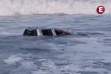Una camioneta pick-up blanca flotando a la deriva en las aguas turbulentas del mar de fondo en la playa de Boca de Pascuales, Tecomán, Colima.