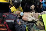 Equipos de rescate trasladan a una persona tras haberla sacado con vida de entre los escombros de un edificio