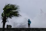 A person looks on as large waves crash against the coast as Typhoon Bavi passes off northeastern Taiwan, in Keelung on July 11, 2026. (Photo by I-Hwa Cheng / AFP)
