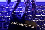 Logotipo de Anthropic en un teléfono sobre un teclado, con una mano robótica al fondo, en una ilustración de Reuters.