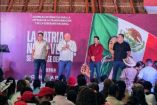 Asamblea informativa en Playa del Carmen con asistentes frente a un escenario que muestra mensajes sobre transformación y soberanía nacional.