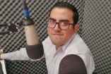 Fotografía del locutor Iván Michel Atilano sonriendo y trabajando en una cabina de radio con un micrófono.