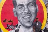 El padre de Daniel Flores posa frente a un mural de su hijo, quien desapareció a la edad de 19 años, en marzo de 2021.