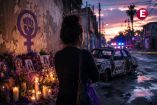 Mujer frente a un memorial por víctimas de violencia en Sinaloa, con presencia policiaca al fondo