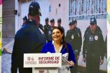 Clara Brugada habla ante un podio durante un informe de seguridad de la Ciudad de México, acompañada por imágenes de policías.