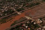 Vista aérea de un río de agua lodosa desbordado sobre una carretera, dividiendo una zona urbana en Loreto, Baja California Sur, tras las lluvias del huracán Polo.