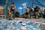 La gente camina por una calle repleta de folletos de campaña electoral en Brasil