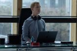 Jeremy Strong como Mark Zuckerberg sentado frente a una laptop en una oficina en El poder de la red.