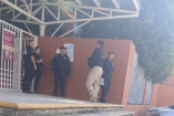 Elementos de seguridad se reúnen en el acceso de una secundaria en Querétaro, tras un reporte por la presunta presencia de un arma en el plantel educativo.