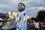 Marcha de trabajadores del IMSS y agremiados del SNTSS exigiendo un salario digno, acompañados de una figura gigante de un trabajador de la salud con cubrebocas.