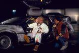 Doc Brown sentado en el DeLorean conversa con Marty McFly durante una escena nocturna de Volver al futuro.