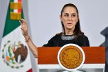 La presidenta Claudia Sheinbaum hablando desde el atril presidencial con el escudo de los Estados Unidos Mexicanos, teniendo la bandera de México de fondo.