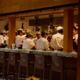 Equipo de cocina de Quintonil trabajando en barra abierta durante un servicio especial, con chefs uniformados en plena coordinación, en un ambiente de alta gastronomía y formación profesional.