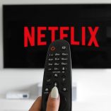 Imagen de una pantalla con el logo de Netflix y en primer plano un control
