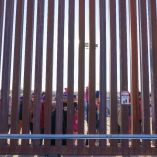 Migrantes asomándose a través de la frontera entre Estados Unidos y México. Foto: AFP.