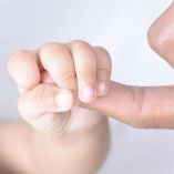 un adulto sujeta la mano de un bebé