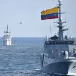 Buques de guerra de la Armada de Colombia navegando en formación sobre el océano Pacífico durante una operación de patrullaje, con bandera nacional izada y helicóptero en el fondo.