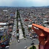 Vista aérea de la escultura del Coyote de Nezahualcóyotl en el Estado de México, con una panorámica urbana al fondo. La imagen muestra tráfico vehicular, alta densidad habitacional y el símbolo cultural del municipio, que ha logrado reducir su tasa de homicidios en 2024 según datos oficiales