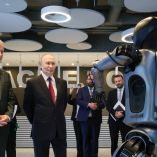 El presidente ruso Vladimir Putin frente al robot humanoide Green durante la exhibición tecnológica de Sberbank en el evento AI Journey 2025 en Moscú, acompañado por German Gref y otros asistentes