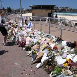People leave floral tributes at the promenade of Bondi Beach in Sydney on December 17, 2025, to honour victims of the shooting that took place there on December 14. Australia held the first funeral on December 17 for victims of the Bondi Beach mass shooting, as large crowds gathered to grieve a rabbi slain in the attack. Sajid Akram and his son Naveed opened fire on a Jewish festival at the famed surf beach on December 14 evening, killing 15 people and wounding dozens more. (Photo by DAVID GRAY / AFP)