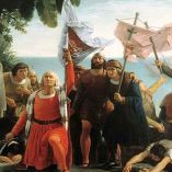 Pintura histórica de 1862 que representa el desembarco de Cristóbal Colón en América en 1492, con estandartes y figuras europeas en la costa, usada como referencia visual sobre la conquista y su interpretación histórica.