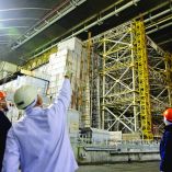A worker points to the damage of the containment vessel following a drone attack on February 14, 2025, on the New Safe Confinement (NSC) which contains radiation from the remains of reactor 4 of the former Chernobyl Nuclear Power Plant, in Chernobyl, on December 22, 2025, amid the Russian invasion of Ukraine. The Chernobyl Nuclear Power Plant director said on December 23, 2025, fully restoring the internal radiation shelter could take three to four years, after a hit earlier this year punched a hole in the outer radiation shell, triggering a warning from the International Atomic Energy Agency (IAEA) that it had "lost its primary safety functions." And warned that another Russian hit could see the inner shell collapse. (Photo by Tetiana DZHAFAROVA / AFP)