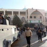 Agentes de seguridad y miembros de la prensa se reúnen frente a la mezquita Imam Ali ibn Abi Talib tras una explosión en el barrio de Wadi al-Dahab de Homs.