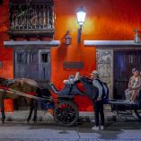 Una pareja se sienta en un carruaje tirado por caballos mientras recorre el centro histórico de Cartagena, Colombia.