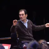 Tugan Sokhiev dirige un ensayo con batuta en mano durante una prueba orquestal en Toulouse, concentrado en marcar el tempo y las entradas de los músicos en una sala de conciertos.