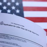 En esta ilustración, tomada el 26 de septiembre de 2025, se ven la bandera de EE. UU. y el formulario de solicitud de visa H-1B de EE. UU.