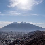 Panorámica de Monterrey vista desde un cerro en la colonia Vista Real, en San Pedro Garza García, con la zona urbana extendida y el Cerro de la Silla al fondo bajo un cielo despejado, en marzo de 2021.