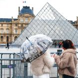 Dos turistas admiran el museo del Louvre desde afuera.
