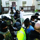 Un agente del ICE aleja a un joven esposado de una casa mientras otros agentes se pelean con testigos.