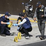 Fiscales y policías recolectan evidencias marcadas en el pavimento durante la investigación del asesinato de un agente policial atribuido a pandillas en Villa Nueva, Guatemala, en medio del estado de sitio decretado por el gobierno.