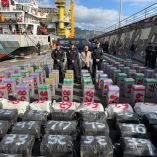 Alijo de paquetes de cocaína incautados por la Policía Nacional en un buque procedente de Brasil, expuestos en un puerto de Tenerife junto a mandos policiales y autoridades durante una operación contra el narcotráfico marítimo.