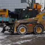 Maquinaria del Departamento de Sanidad de Nueva York limpia la nieve de una acera en Hudson Yards mientras un autobús circula al fondo, en medio de temperaturas bajo cero durante una ola de frío invernal en la ciudad.
