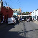 Bloqueo de calles en el Centro Histórico de la ciudad de Oaxaca por maestros de la Sección 22, con autobús detenido y peatones durante la protesta por el pago de horas-clase adeudadas.