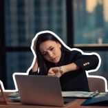 Empleada revisa la hora mientras trabaja frente a una computadora, ejemplo de horas extra en México dentro de una jornada laboral extendida